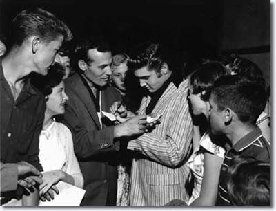 Carl Perkins and Elvis Presley sign autographs at Overton Park Shell on the night of June 1, 1956. Some 5,000 teenagers turned out that night for two hours of rock and roll by various artists including Perkins. Elvis Presley made a surprise appearance at the show, but did not perform.
